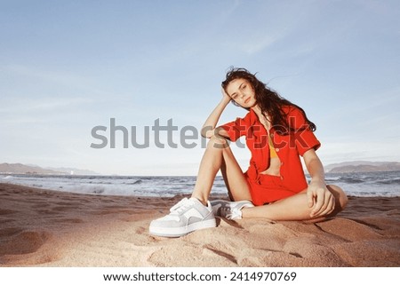 Relaxed Woman on the Beach, Fashionably Sitting and Smiling: a Summer Vacation with Sand, Sea, and Wide Angle Joy