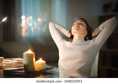 Relaxed woman resting sitting on a chair in the night with candles at home
