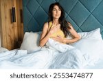 Relaxed woman sitting in the bed in the morning  and making breathing exercises 