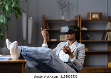 Relaxed young african american female employee using VR headset for relaxation at workplace, smiling black business woman meditating in virtual reality while relaxing with feet on office desk - Powered by Shutterstock