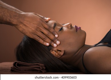 Relaxed Young African Woman Receiving Forehead Massage In Spa
