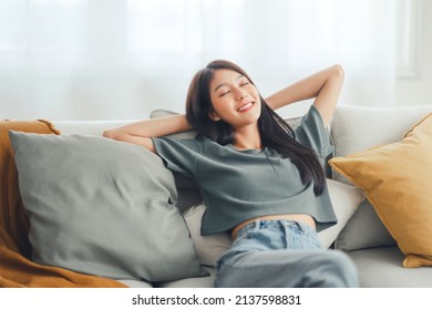 Relaxed young asian woman enjoying rest on comfortable sofa at home, calm attractive girl relaxing and breathing fresh air in home, copy space. - Shutterstock ID 2137598831