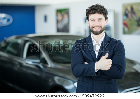 relaxed young businessman or salesman with hands crossed in front of car
