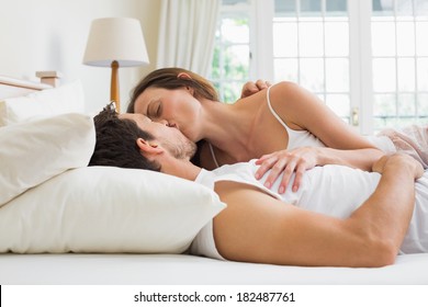 Relaxed Young Couple Kissing In Bed At Home