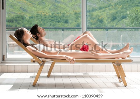Relaxed young couple sunbathing on sunbeds in the nature
