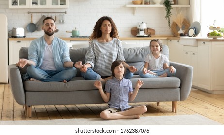 Relaxed young family with cute children sitting and meditating with closed eyes. Attractive wife and husband with son and daughter do breathing exercises. Parents with kids doing yoga together. - Shutterstock ID 1762387076
