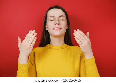 Relaxed Young Female Model Enjoying Good Smell Or Pleasant Fragrance, Serene Mindful Woman Taking Deep Breath Feel No Stress Free Inhaling Fresh Air Relaxing Isolated On Red Studio Background