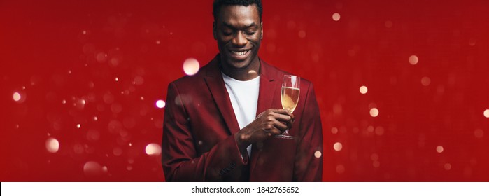 Relaxed Young Man With A Glass Of Champagne And Thinking Against Christmas  Background. Man Remembering A Special Moment While Having A Glass Of Champagne.