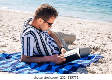relaxed young man reading a book on the beach - Powered by Shutterstock