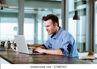 Relaxed Young Professional Surfing The Internet On His Laptop In A Cafe