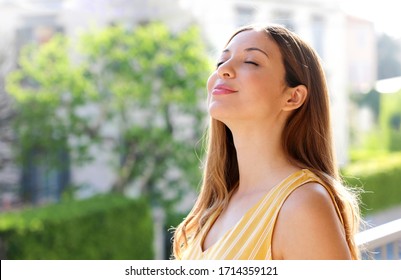 Relaxed young woman breathing fresh air on balcony in the morning
