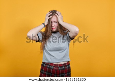 Relaxed young woman in casual clothes keeping eyes closed, with hands on head isolated on orange wall background in studio. People sincere emotions, lifestyle concept.