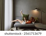 Relaxed young woman enjoying cozy indoor space with green pillow, casual outfit, and natural light, embodying comfort and tranquility in a modern setting