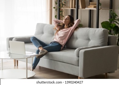 Relaxed Young Woman Leaned On Couch Closed Eyes Putting Hands Behind Head Enjoy Fresh Air, Freelancer Resting From Work In Modern Cozy Living Room Alone, Daydream Day Nap, Fall Asleep Or Pause Concept