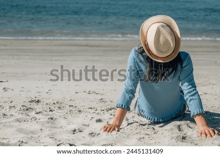relaxed young woman sitting on the beach looking at the sea