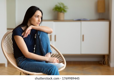 Relaxed Young Woman Thinking Sitting In Modern Armchair Relaxing At Home. Free Space For Text