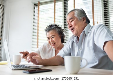 Relaxing Asian Senior couple making video call and talking with family on Laptop computer. Happy Smiling Japanese Elderly man and woman enjoy with internet technology on table at home. Lifestyle, fun