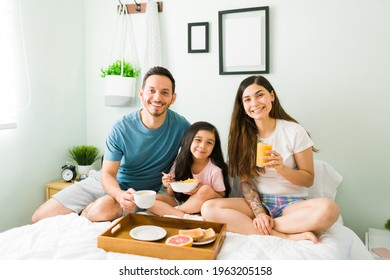 Relaxing breakfast in bed. Latin family smiling and enjoying a delicious morning meal after waking up during the morning weekend