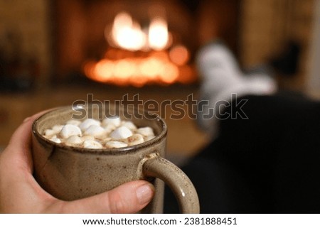 Relaxing by the fireplace fire in winter with mug of hot cocoa chocolate while wearing fuzzy socks