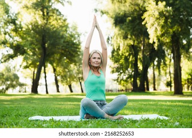 Relaxing caucasian mature woman practicing meditation, doing breathing exercises on fitness mat in forest park outdoors. - Powered by Shutterstock