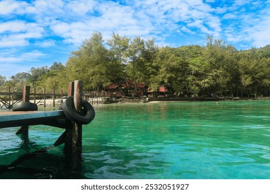 Relaxing day on Mamutik Island, Malaysia with clear waters, lush greenery, and wooden jetty under a bright sky - Powered by Shutterstock