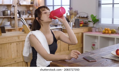 Relaxing In Dining Room After Run. Portrait Slender Girl Prizing Off Tumbler Lid And Drinking Refreshing Water. Genuine Lifestyle