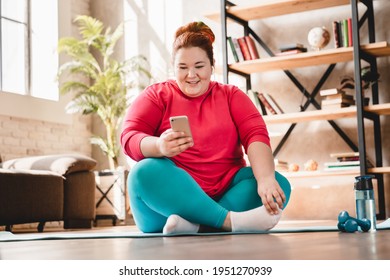 Relaxing Fat Plus Size Caucasian Woman Resting After Hard Fitness Training At Home Using Smart Phone. Chubby Obese Woman Wants To Lose Weight And Burn Calories