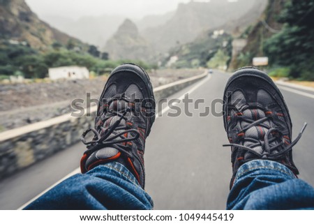 Relaxing feet with trekking footwear hanging from pickup car after long trek way. Santo Antao Island, Cape Verde