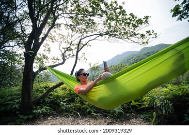 Relaxing in hammock hand using smartphone in tropical forest - Powered by Shutterstock