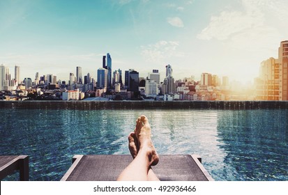 Relaxing In Holidays, Panoramic Feet On Sun Bathing Bed At Swimming Pool On Roof Top In The City