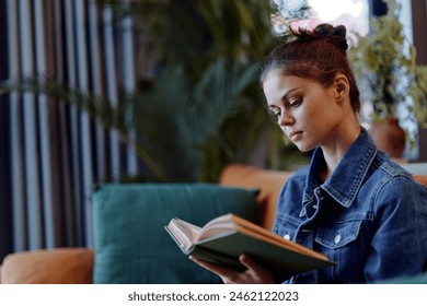 Relaxing at Home Woman Reading Book on Couch in Front of Plant in Cozy Living Room Setting - Powered by Shutterstock