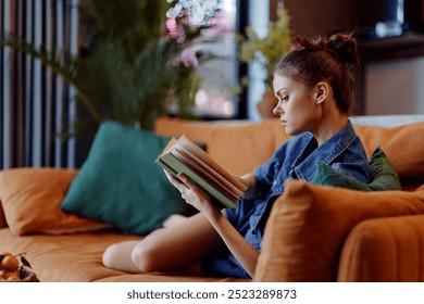 Relaxing at Home Woman Reading Book on Couch with Plants in Background Through Window - Powered by Shutterstock