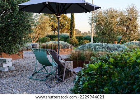 A relaxing image. Tuscany, Italy. The garden of a country house in the famous Tuscan hills. Sun chairs and umbrella in an Italian garden.