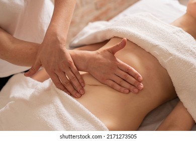 relaxing massage and body shaping massage, lymphatic drainage, manual and aesthetic procedures, hands massaging belly in the spa salon