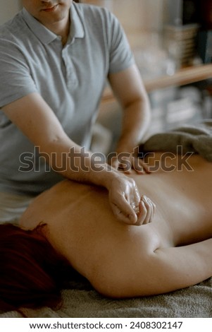 Relaxing massage in the salon. Male masseur massages his back