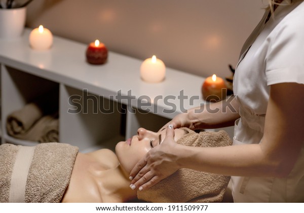 Relaxing massage. Woman receiving head massage at\
spa salon, side view.