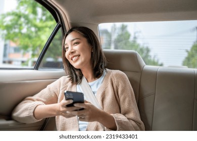 Relaxing moment of beautiful woman sitting in car back seats using smartphone play social media with safety belt and look out the window. Female happy in car traveling on the road to destination. - Shutterstock ID 2319433401