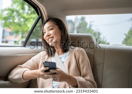 Relaxing moment of beautiful woman sitting in car back seats using smartphone play social media with safety belt and look out the window. Female happy in car traveling on the road to destination. Stock foto © 