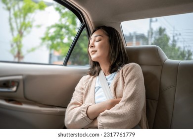 Relaxing moment of beautiful woman sleeping in car back seats with safety belt. Female happy in car while traveling on the road to your destination.