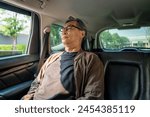 Relaxing moment of mature man sleeping in car back seats with safety belt. old man happy in car while traveling on the road to destination.