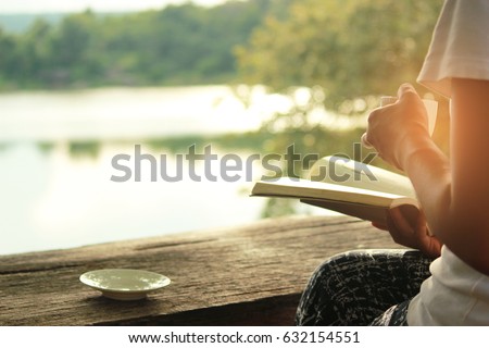 Relaxing moments , Cup of coffee and a book on wooden table in nature background, color of vintage tone and soft focus.