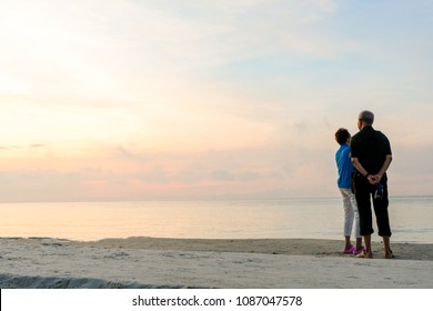 Relaxing moments, loving mature couple retire. Rear view of mature couple at sand beach, enjoying in nature during vacation.