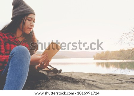 Relaxing moments, Young woman reading a book by the lake. Solo relaxation, color of Hipster Tone.