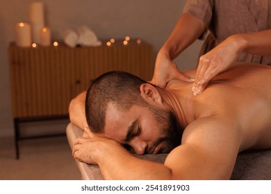 Relaxing neck massage, healthy massaging rehab concept. Close-up hands of woman masseur doing wellness medical relaxing massage for male patient in dark medical office in shadow. Copy ad text space - Powered by Shutterstock