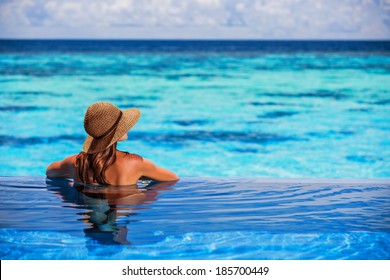 Relaxing On Beach Resort, Back Side Of Sexy Woman Enjoying Seascape From Endless Pool, Luxury Summer Vacation, Travel And Tourism Concept