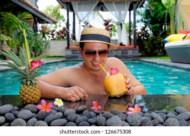 Relaxing On Holiday, Handsome Man Relaxing In Swimming Pool And Drinking Coconut Cocktail At A Luxury Villa On Bali Island