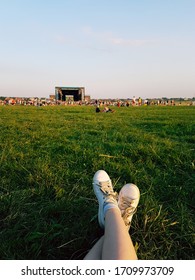 Relaxing At Open Air Music Festival In Ukraine. Traditional Celebration With Famous Music Groups Performing On Stage. Listening To Live Music Looking At Crowd When Laying Down On The Green Grass Lawn.