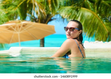 Relaxing Sly Woman In Luxury Hotel Pool On Holidays Vacation Travel. Happy Young Female Person Enjoying In Pool Spa At Hotel In Island 