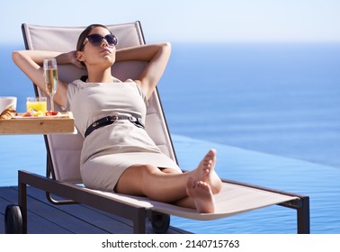 Relaxing While On Holiday. A Posh Young Woman Reclining On A Deck Chair With Her Hands Behind Her Head.