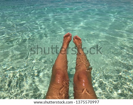 Relaxing woman legs close up on a clear cristal water.